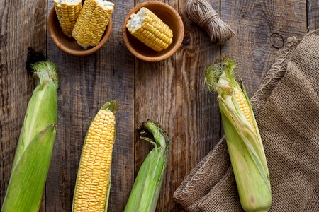 Organic farm food. Cutted corn cobs on rustic wooden background top view.