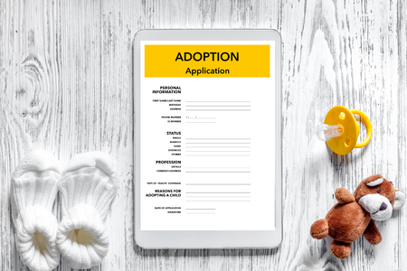 Adoption application near toy on light wooden table background top view.の写真素材