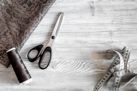 Clothing designer workplace. Fabric. measuring tape, thread and sciccors on light wooden background top view copyspaceの写真素材