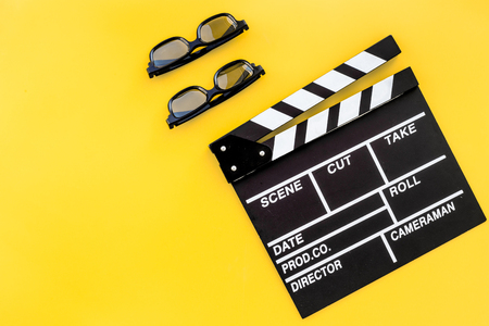 Filmmaker accessories. Clapperboard and glasses on yellow background top view.の写真素材