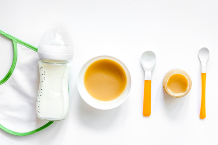 Preparing to feed baby. Puree, spoon and bib on white background top view.の写真素材