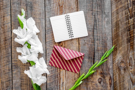 Congratulation. Envelope, notebook and box in kraft paper near flower gladiolus on wooden table top viewの写真素材