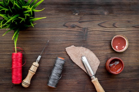 Leather craft. Tanner's tools on dark wooden table background top view.の写真素材