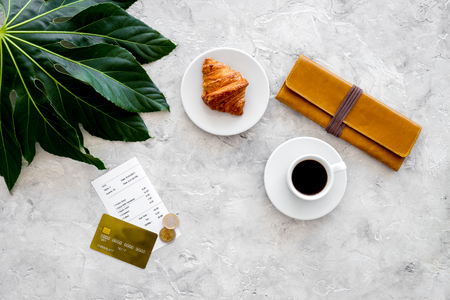 Pay bill at cafe by card. Purse, bill and bank card near coffee and croissant on grey stone table top view.の写真素材