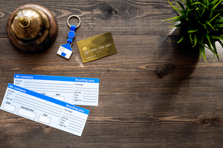 Preparing to trip. Book hotel and tickets. Airplane tickets near service bell and bank card on dark wooden table top view.の写真素材