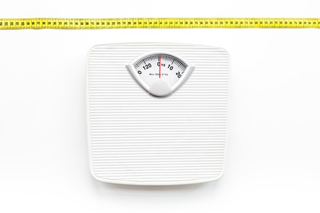 Bathroom scale and measuring tape on white background top viewの写真素材