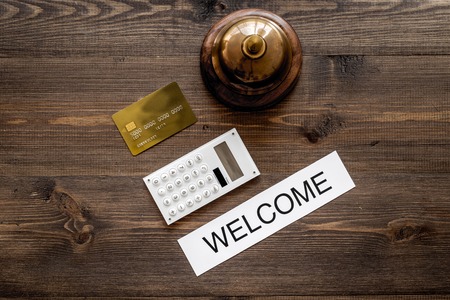 Check in at the hotel and pay. Word welcome near service bell and bank card on dark wooden table background top viewの写真素材