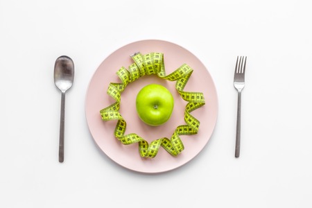 Slimming diet. Apple at plate on white background top view.の写真素材