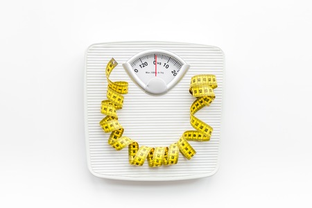 Bathroom scale and measuring tape on white background top viewの写真素材