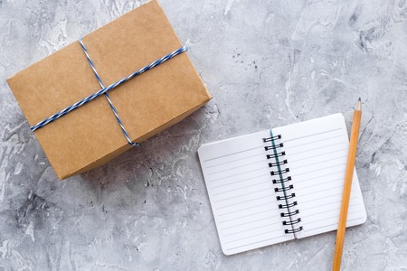 Celebration accessories. Box in kraft paper and notebook on grey stone table top view copyspaceの写真素材