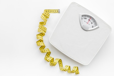 Bathroom scale and measuring tape on white background top view copyspace