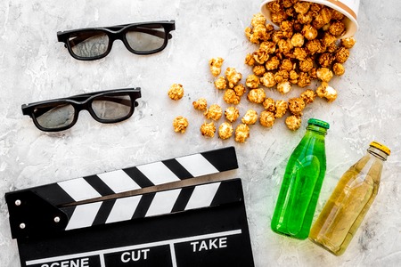 Food for watching film. Popcorn and soda near clapperboard, glasses on grey background top view copyspaceの写真素材