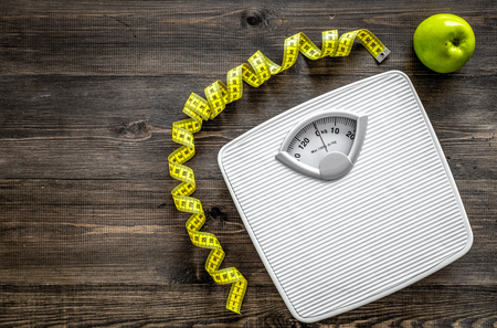 Lose weight concept. Bathroom scale, measuring tape, apples on wooden background top view.の写真素材