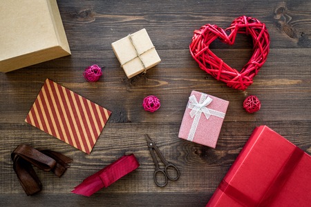 Packaging gift. Colored gift boxes, sciccors, ribbon, thin cord on dark wooden background top view