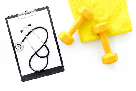 Sport and health. Fitness. Dumbbells and stethoscope on white background top viewの写真素材