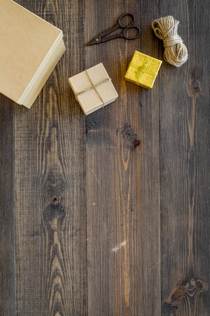 To wrap gift. Boxes, kraft paper, ribbon, sciccors on wooden background top view.の写真素材