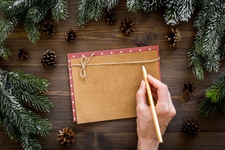 Mockup for new year 2018. Hand writes on sheet of paper near spruce branches, pine cone on wooden background top view.の写真素材
