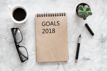 Words Goals for 2018 writting in notebook near glasses and cup of coffee on grey stone background top view mockup.の写真素材