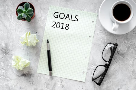 Goals list for 2018. Sheet of paper near pen and cup of coffee on grey stone background top view.の写真素材