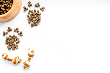 large plastic bowl of pet - dog food spilling in paw print on white table background top view mockupの写真素材