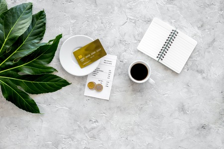 Pay restaurant bill. Bill, bank card, coins near cup of coffee on light table top view copyspace