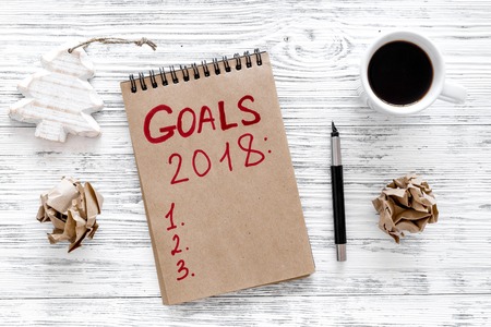 Make a goals list for 2018. Notebook near pen and cup of coffee on grey wooden background top view.の写真素材