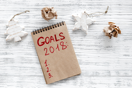 Make a goals list for 2018. Notebook and christmas decoration on wooden background top view.の写真素材