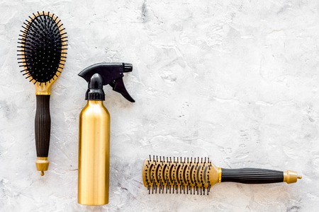 golden combs and spray for hairdresser work set on stone desk background top view mock-upの写真素材