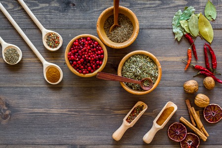 Colorful dry herbs and spices for cooking food on wooden kitchen table background top viewの写真素材