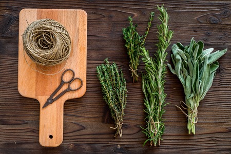 fresh herbs and greenery for spices and cooking on wooden kitchen desk background top viewの写真素材