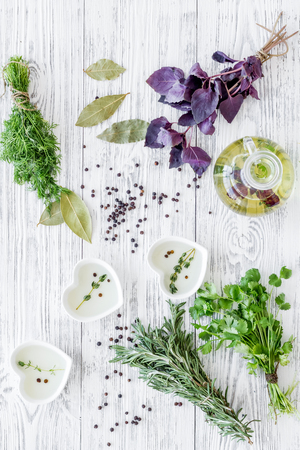 natural oil and fresh greenery for restaurant cooking with spices on wooden kitchen table background top viewの写真素材