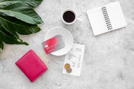 How much. Restaurant bill, bank card, wallet, coins near cup of coffee on light stone table top view copyspaceの写真素材