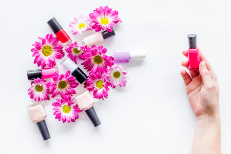 Choose nail polish for manicure. Woman hand hold bottle of polish on white background top view.の写真素材