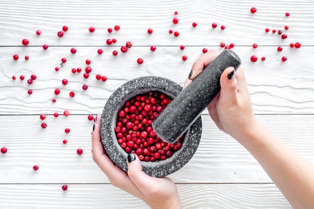 mortar with berries, herbs and spices ingredients on white wooden background top viewの写真素材