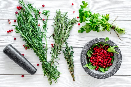 berries and herbs in mortar for making spices in food set on white wooden table background top viewの写真素材