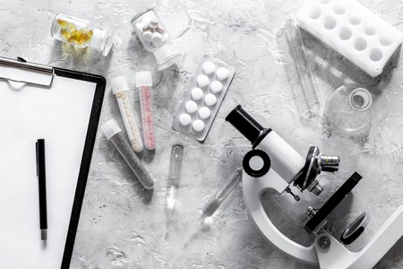 Laboratory test. Microscope, pills, test tube on grey stone background top view.の写真素材