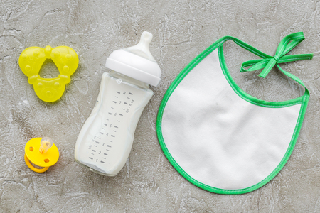 bottle with breastmilk and infant formula powdered healthy food, toys and bib on stone desk background top viewの写真素材