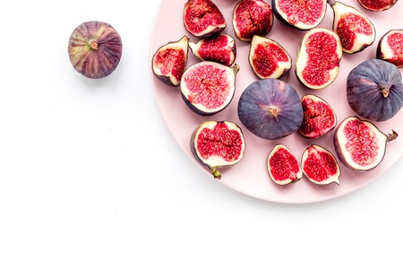 Plate of fresh blue figs on white background top view.