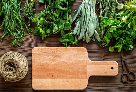 flat lay with fresh herbs and greenery for drying and making spices set on wooden kitchen table background mock-upの写真素材