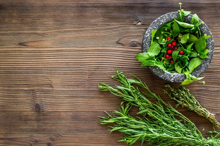 mortar with berries, herbs and spices ingredients on wooden desk background top view mock-up