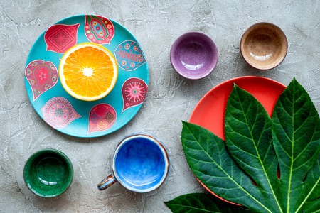 Tableware pattern. Cups and plates decorated by exotic leaves and fruits on grey background top view.の写真素材