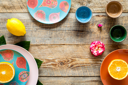 Colored cups and plates near tropical leaves and fruits on wooden background top view.の写真素材