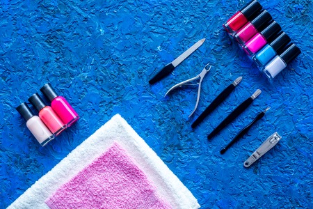 Manicure in beauty salon. Tools for manicure, nail polish and towels on blue desk top view.の写真素材