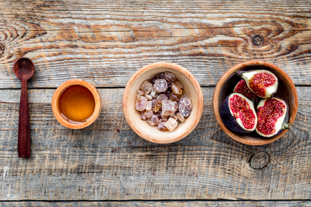 Make jam. Fresh blue figs in bowl and honey on wooden background top view.の写真素材