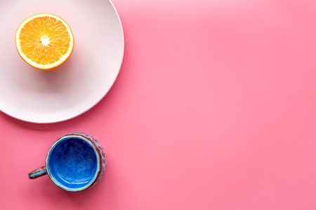 Colored cup and plate decorated by orange on pink background top view copyspaceの写真素材