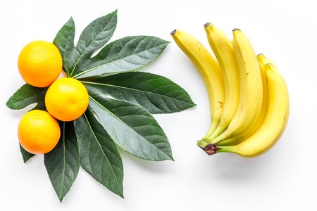 Tropical fruits background. Bananas and oranges on white background top viewの写真素材