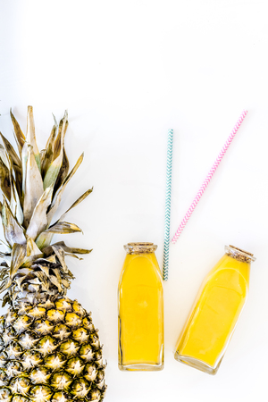 Pineapple juice in glass and bottle near whole pineapple and tubule on white background top view.の写真素材