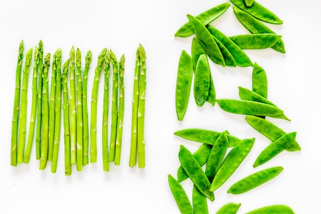 Fresh green pea pods and sprout of asparagus on white background top view