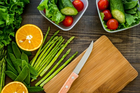 Healthy meal in containers. Salad with tomato and cucumber in cotainers on wooden background top view mockupの写真素材