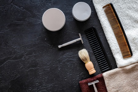 At the barbershop. Razors, shaving brush, comb, wax, towel on black background top view copyspaceの写真素材